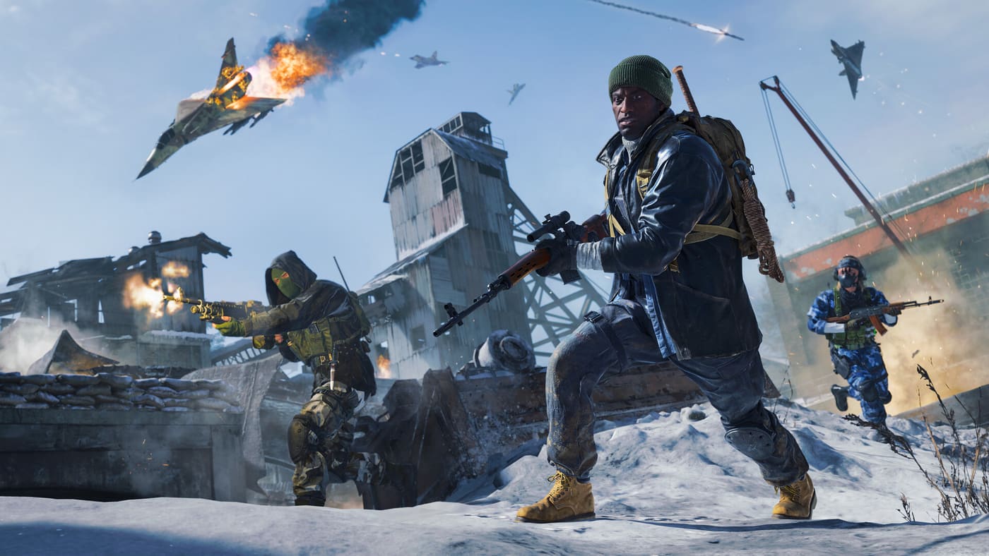 Three Call of Duty operators fight at close range across a snow-covered industrial yard, one firing from behind a concrete wall while a burning fighter jet falls out of the sky behind them. Official Call of Duty screenshot supplied by Activision.
